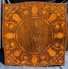 The spectacular inlay/marquetry in the top is inset into a single "bookmatched"* piece of quarter sawed white oak with "combed" figure giving it a mirrored look.
* From Wikipedia: Bookmatching is the practice of matching two (or more) wood or stone surfaces, so that two adjoining surfaces mirror each other, giving the impression of an opened book.